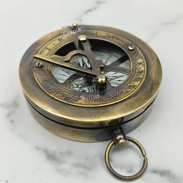 Angled view of the closed black antique sundial compass, highlighting its solid brass construction and pocket-watch style.