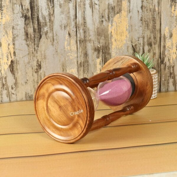 Close-up view of the polished rosewood base of the large pink sand hourglass, showing the wood grain.