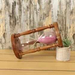 The decorative rosewood hourglass used as a stylish accent piece on a desk next to a small plant.