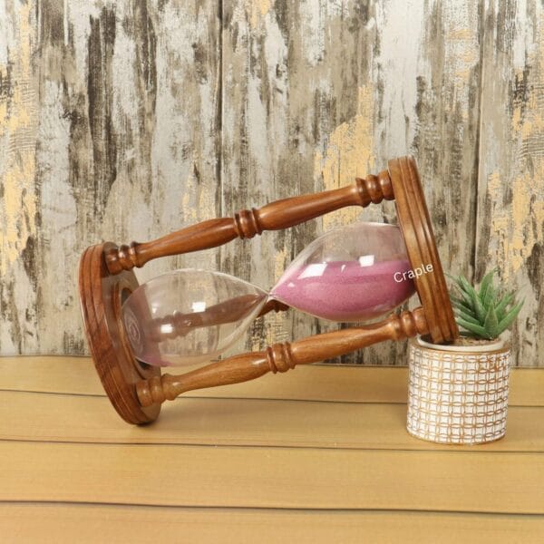 The decorative rosewood hourglass used as a stylish accent piece on a desk next to a small plant.