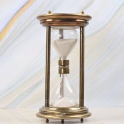 Large vintage-style 5-minute hourglass with a shiny brass finish, steel pillars, and white sand.