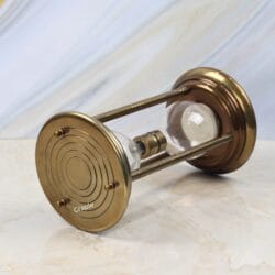 The 5-minute brass and steel hourglass lying on its side on a marble surface.