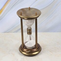 High-angle view of the large decorative sand timer with white sand and an antique brass frame.