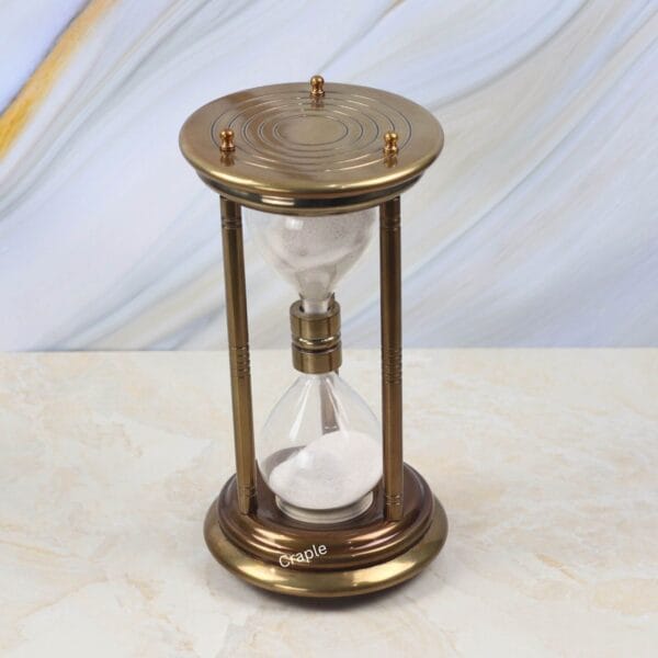 High-angle view of the large decorative sand timer with white sand and an antique brass frame.