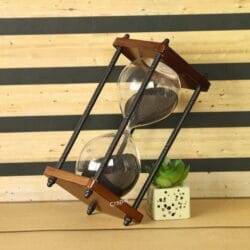 The 10-minute black sand timer used as a decorative piece on a desk next to a small plant.