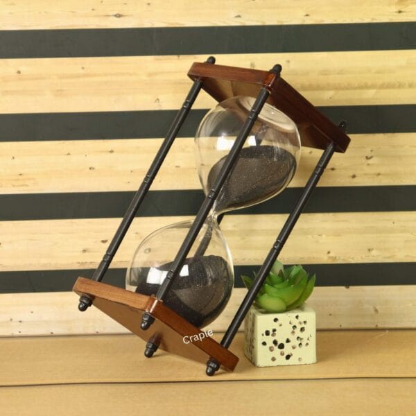 The 10-minute black sand timer used as a decorative piece on a desk next to a small plant.