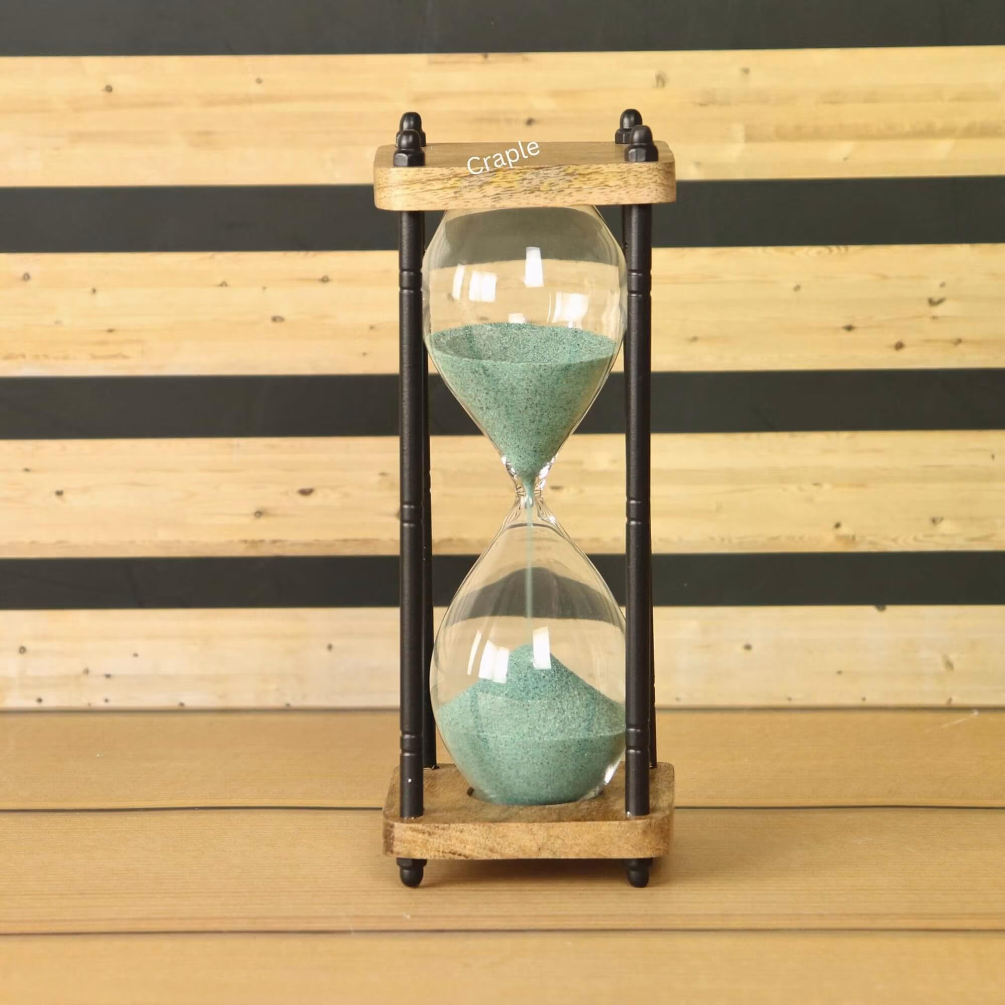 A rustic 10-minute hourglass with dark green sand, framed by natural wood and black antique-finish brass pillars.