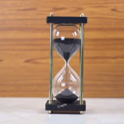 A modern 15-minute hourglass with black sand, framed by black wooden bases and nickel-plated brass pillars.