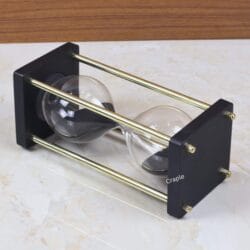 The 15-minute black sand hourglass lying on its side, showcasing its sturdy and elegant frame construction.