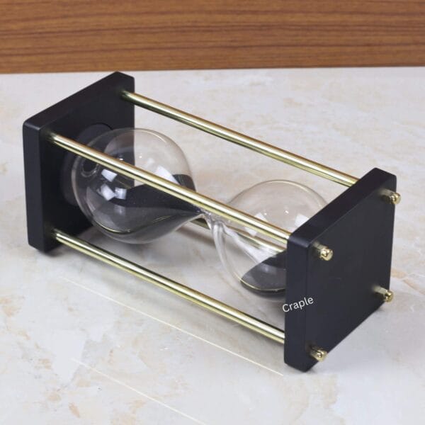 The 15-minute black sand hourglass lying on its side, showcasing its sturdy and elegant frame construction.