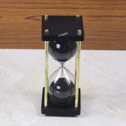 A top-down view of the hourglass, showing the square black wooden top and the upper bulb filled with black sand.