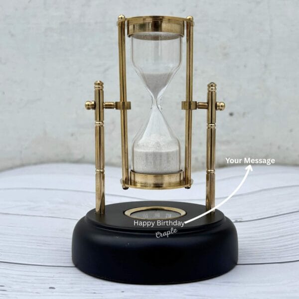 The black wooden base of the hourglass showing the customizable with a "Happy Birthday" message, demonstrating it is engravable.