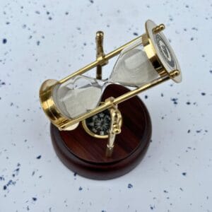 The rotating brass hourglass tilted to show the functional built-in magnetic compass in the wooden base.