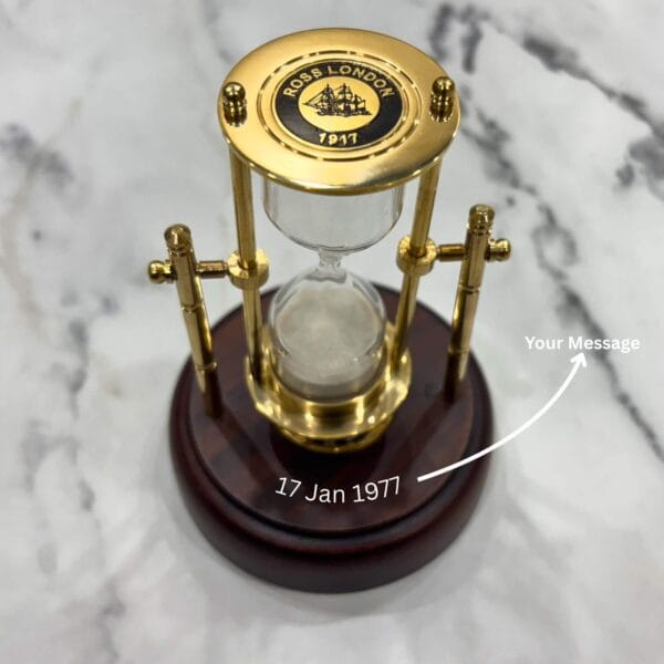 A close-up of the polished brass top plate of the rotating hourglass, featuring a "Ross London 1897" emblem.