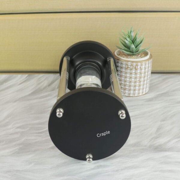 Close-up of the black base of the floating hourglass, showing the steel hardware and minimalist design.