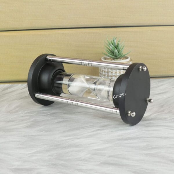 Angled side profile of the white sand floating hourglass, highlighting its sleek steel pillars and black frame.