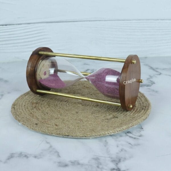 The wooden and brass 3-minute sand timer resting horizontally, showcasing its classic design and purple sand.