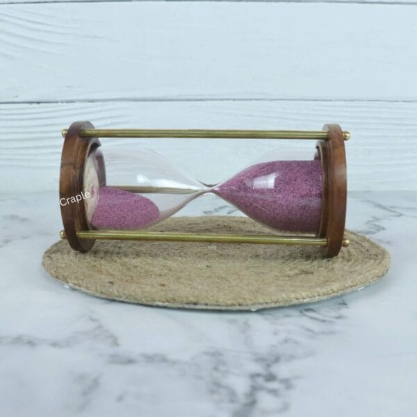Side profile of the vintage hourglass, showing the purple sand flowing between the glass bulbs within the brass frame.