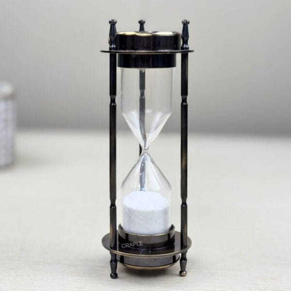 Front view of an antique brass 3-in-1 desktop accessory, focusing on the 3-minute white sand hourglass.