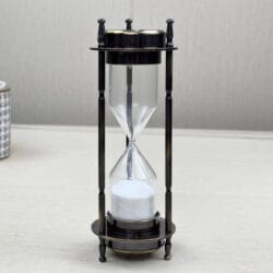 Side profile of the antique brass sand timer, showing the slender pillars and classic finials.