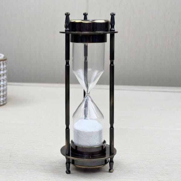 Side profile of the antique brass sand timer, showing the slender pillars and classic finials.