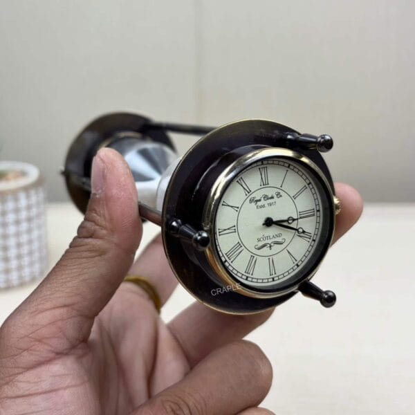 The top of the hourglass held sideways, showing a close-up of the vintage analog clock face.