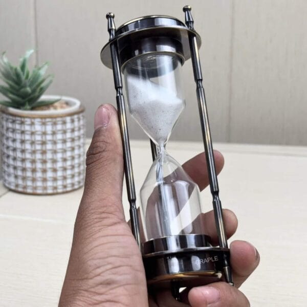 Full view of the 3-in-1 brass hourglass timer held in hand to showcase its design and scale.