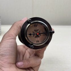 Detailed close-up of the functional compass dial on the base of the antique brass hourglass.