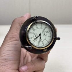 Detailed close-up of the analog clock face with Roman numerals on top of the brass hourglass.