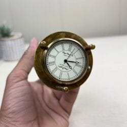 Close-up of the vintage Roman numeral clock on the end of the multifunctional brass hourglass, held in a hand.
