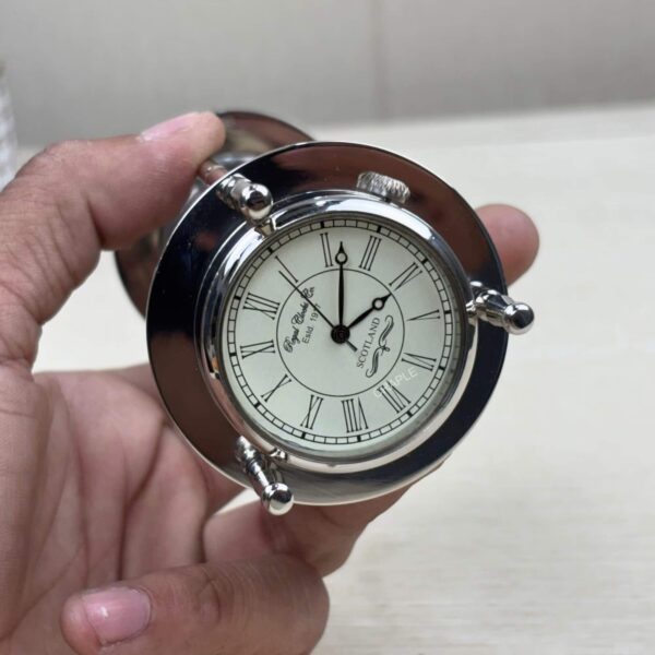 Close-up of the top of the hourglass, showing the integrated analog clock with Roman numerals.