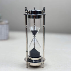 Side profile of the 3-minute black sand timer with its nickel-finish brass frame standing upright.
