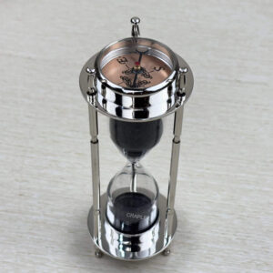 A multifunctional 3-in-1 desktop tool featuring a black sand hourglass, a compass, and a clock, all in a polished nickel-finish brass frame.