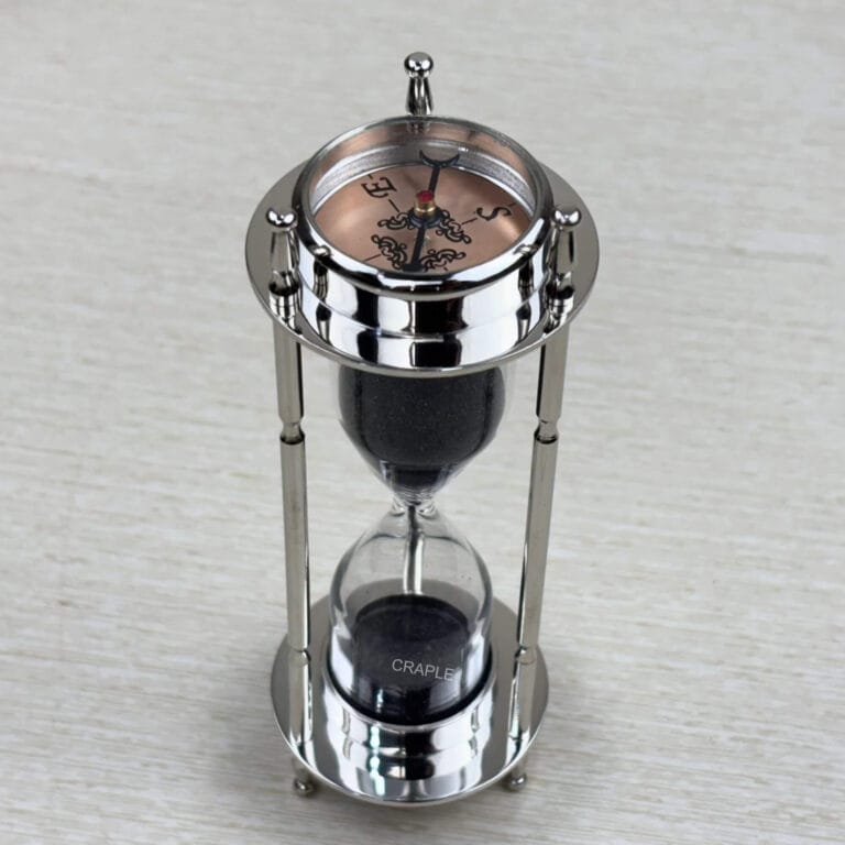 A multifunctional 3-in-1 desktop tool featuring a black sand hourglass, a compass, and a clock, all in a polished nickel-finish brass frame.