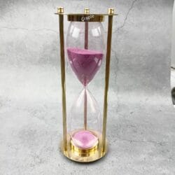 Elegant 30-minute hourglass sand timer featuring a polished brass frame and vibrant light pink sand.