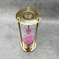 Top view of the brass hourglass, showing the "Old Sand Watch" engraved compass rose design on the top plate.