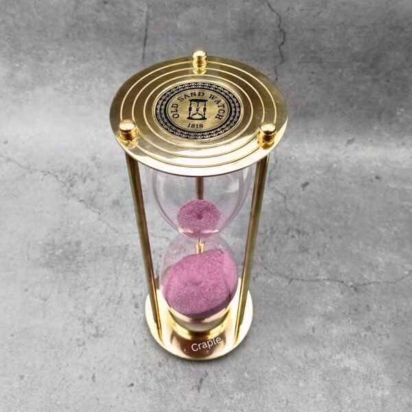 Top view of the brass hourglass, showing the "Old Sand Watch" engraved compass rose design on the top plate.