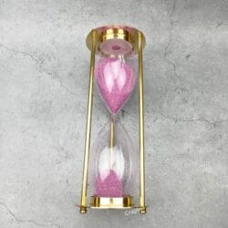 The 30-minute brass hourglass shown after the pink sand has fully flowed to the bottom bulb.