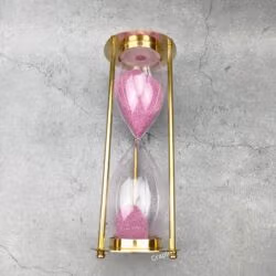 The 30-minute brass hourglass shown after the pink sand has fully flowed to the bottom bulb.