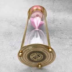 Close-up of the engraved top plate of the vintage-style brass hourglass.