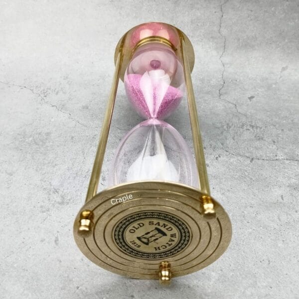 Close-up of the engraved top plate of the vintage-style brass hourglass.