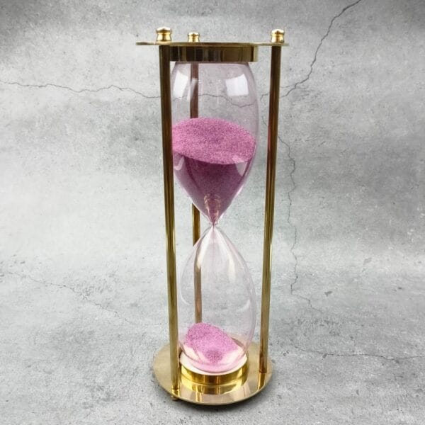 Full view of the decorative 30-minute brass sand timer with pink sand.
