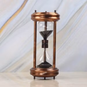 A 5-minute hourglass with an antique copper finish steel frame and black sand, standing on a marble surface.