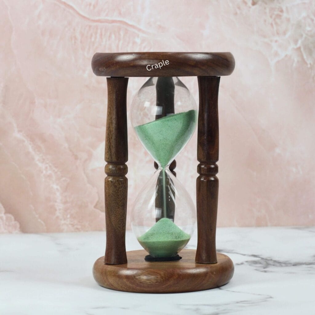 An antique-style 5-minute hourglass with a polished rosewood frame, turned pillars, and light green sand.