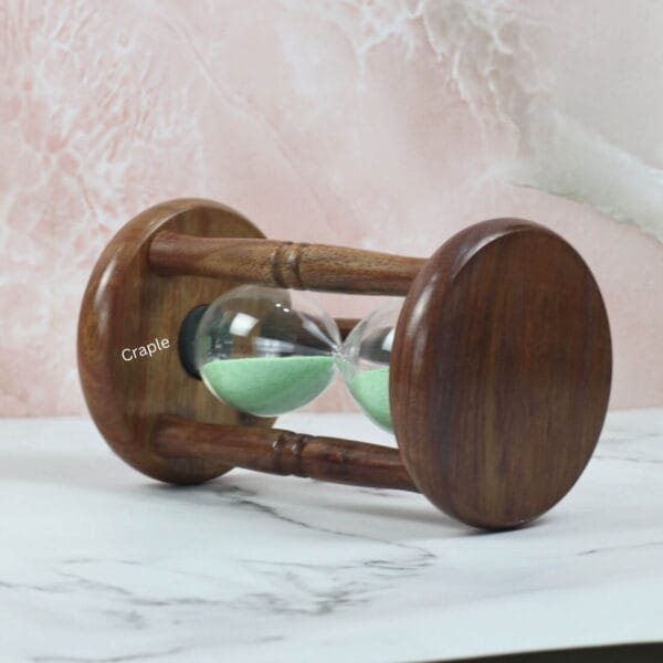 The rosewood hourglass resting on its side, showcasing the rich wood grain of the circular base and pillars.