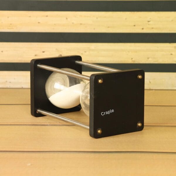 Close-up of the square black wooden base and nickel-finish hardware of the 5-minute sand timer.