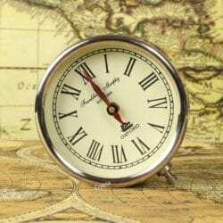 The nickel-finished round desk clock with a classic Roman numeral face, shown detached from its stand.