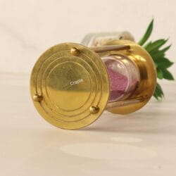 Close-up of the engraved circular details on the polished brass base of the 1-minute hourglass.