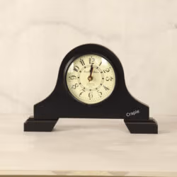 A classic black antique wooden desk clock with an arched top and a vintage-style off-white dial with Arabic numerals.