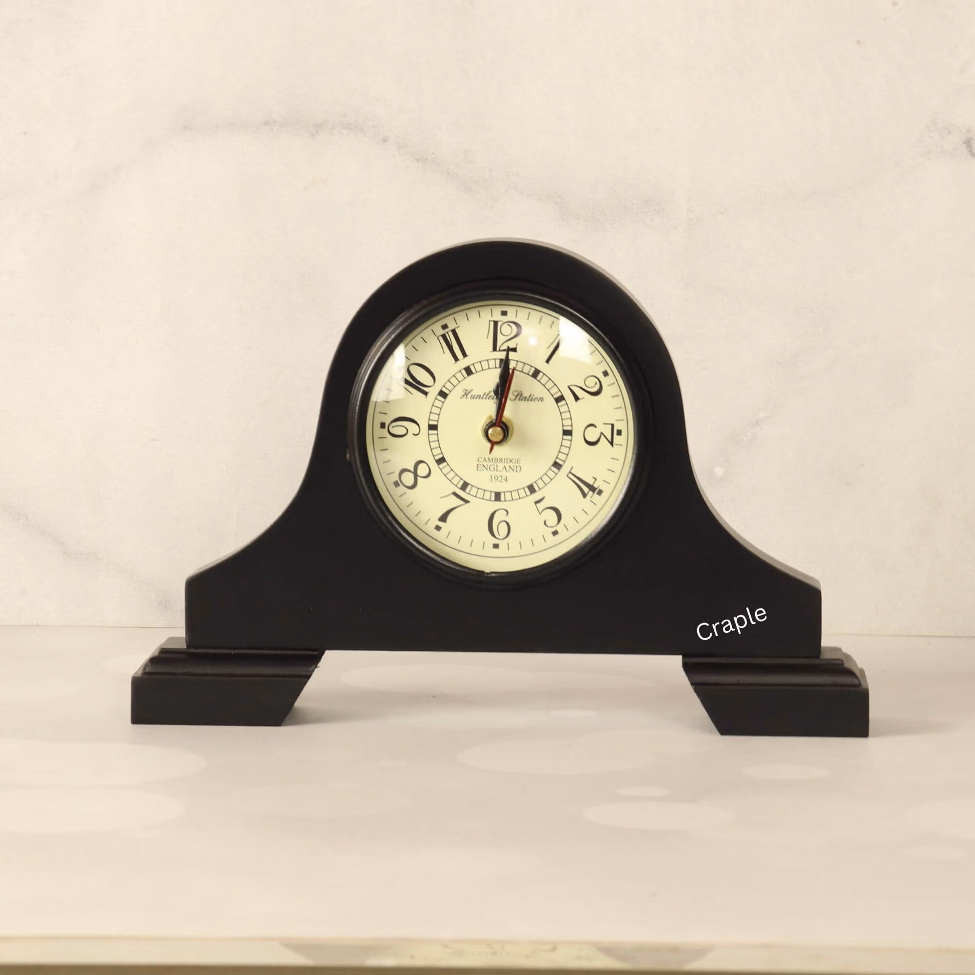 A classic black antique wooden desk clock with an arched top and a vintage-style off-white dial with Arabic numerals.